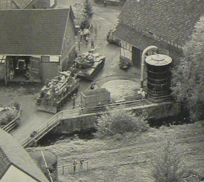 A tank and an armored personnel carrier, just two of the 3,500 vehicles used in Autumn Forge, rumble through a small village. From Air Man.