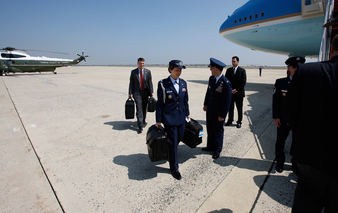 Military Aide Lt. Colonel Gina Humble carries the Football as Air Force One prepares for departure at Andrews Air Force Base. This photo, like several