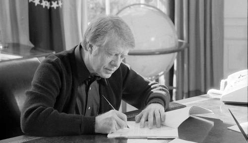President Jimmy Carter annotates a document while working at his desk in the Oval Office