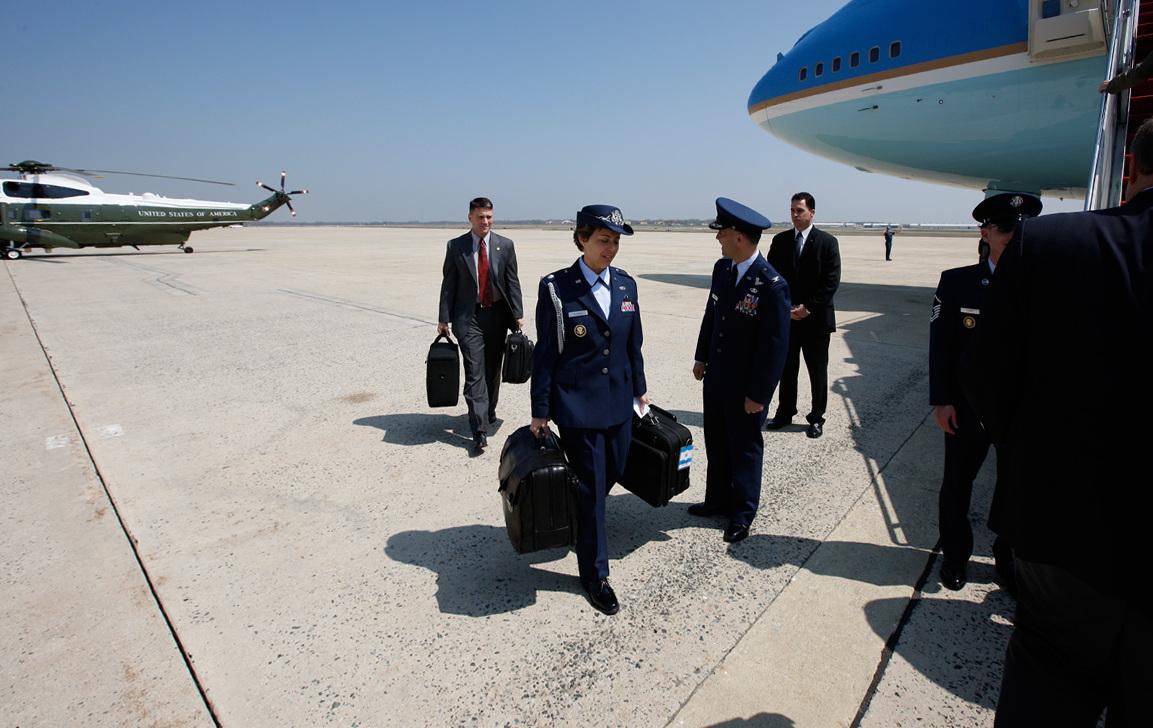Air Force One readies for departure from Andrews Air Force Base for Waco, Texas, 10 April 2008. Military Aide Lt. Colonel Gina Humble carries the Football
