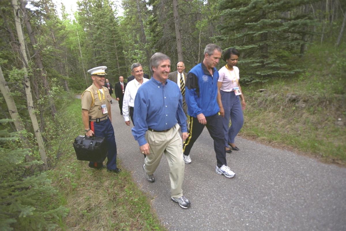 During meetings of the G-8 Economic Summit in Kananaskis, Canada, President Bush walks on the Delta Lodge grounds with Secretary of State Condoleezza Rice, White House Chief of Staff Andrew Card, and others, 25 June 2002. A unidentified Military Aide carries the football. Photo number P19106-17