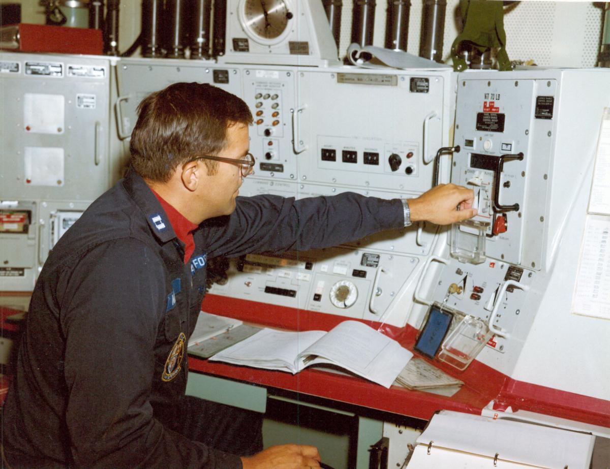 Launch control officer, seated at launch control panel, turns switch to start launching sequence. Testing operational readiness of Minuteman crews using Modified Operational Missiles