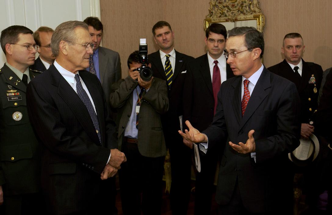 Defense Donald H. Rumsfeld (left) listens as President Álvaro Uribe (right)